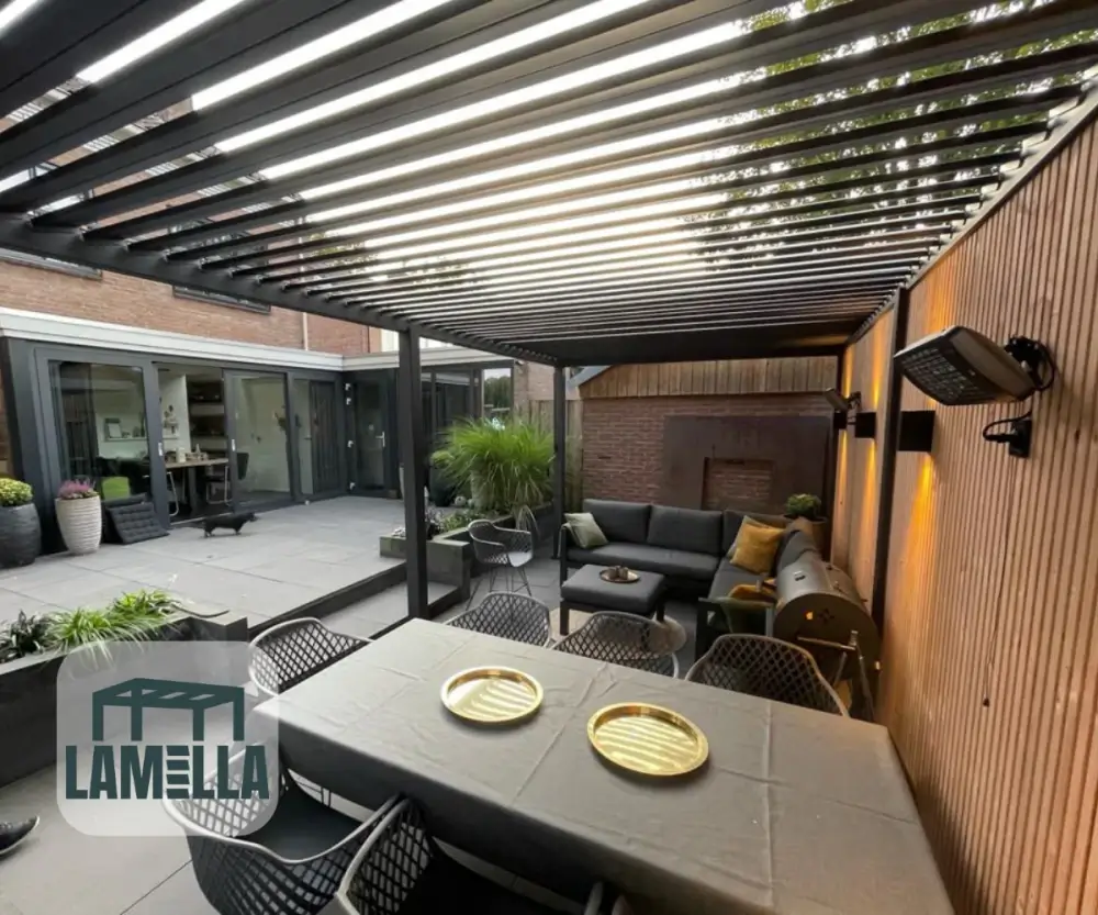 Een modern buitenterras met een pergola met lamellendak. Er is een eettafel met twee gouden borden en zwarte stoelen, en een gezellige zithoek met een bank. Planten en sfeerverlichting versterken de uitnodigende sfeer van de ruimte.