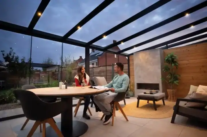 Moderne veranda met glazen dak en zithoek als uitbreiding van woonruimte