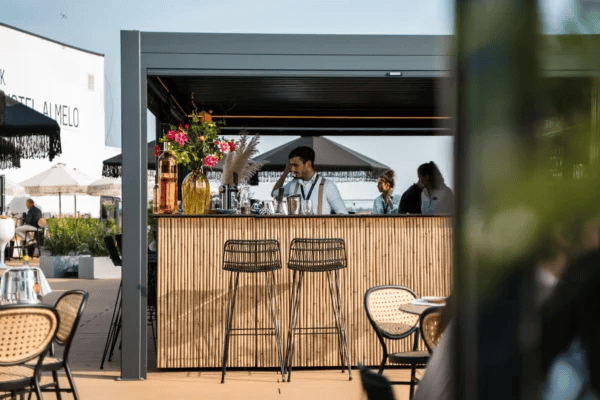Buitenkeuken met bar onder lamellenoverkapping op terras