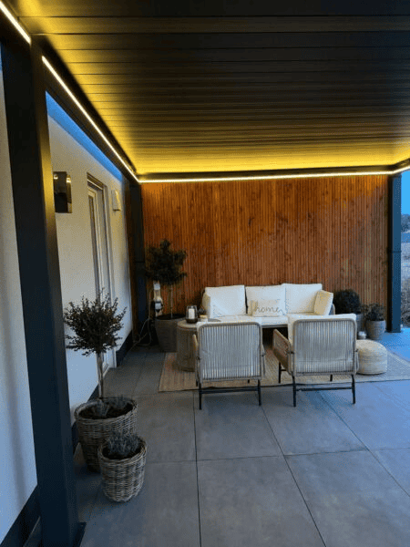 Moderne lamellen overkapping met warme sfeerverlichting en loungehoek