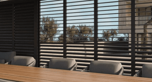 Tuinoverkapping met zwarte lamellen en comfortabele stoelen