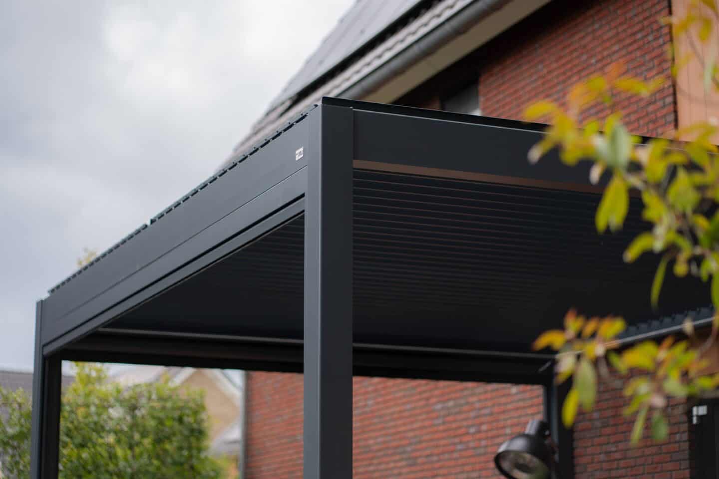 Elegante zwart metalen terrasoverkapping met lamellenpanelen, ideaal voor elegant buitenleven.