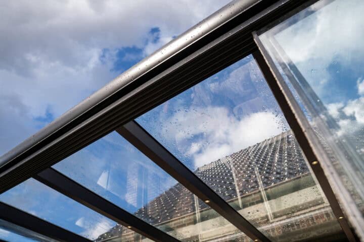 Heldere glazen overkapping met regenwater en uitzicht op de hemel.